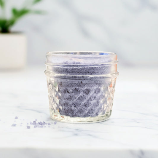 Glass jar with textured lid on a marble surface with a blurred background
