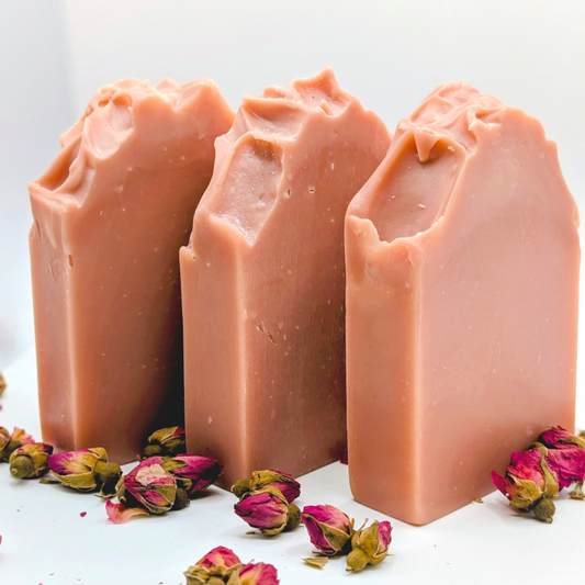 Three bars of pink soap with dried flowers on a white background