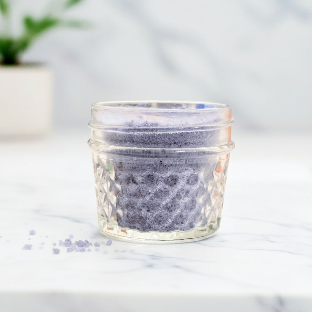 Glass jar with textured lid on a marble surface with a blurred background