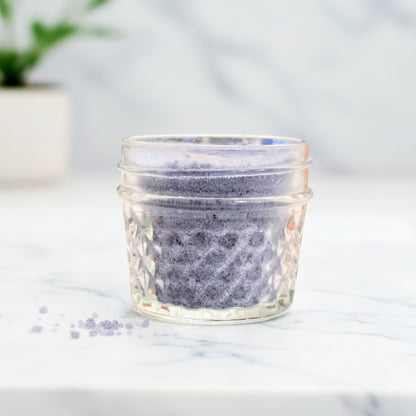 Glass jar with textured lid on a marble surface with a blurred background
