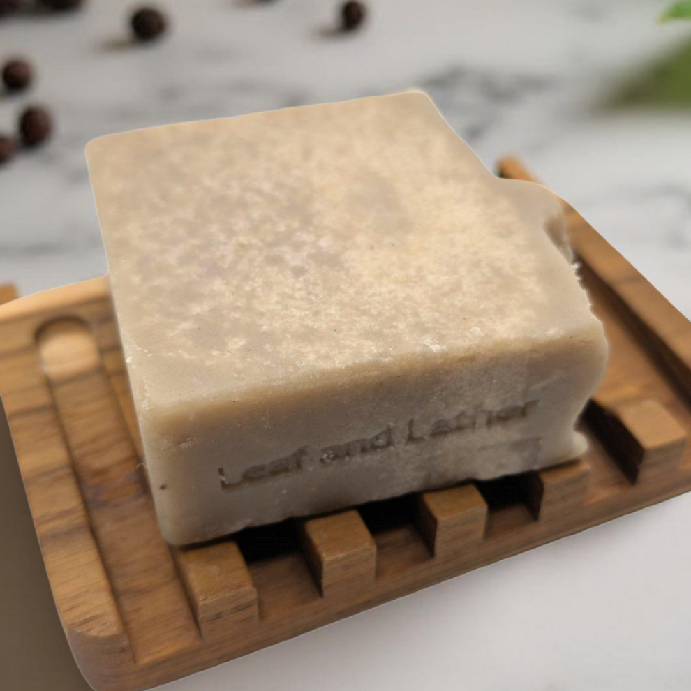 Bar of soap on a wooden soap dish with a blurred natural background