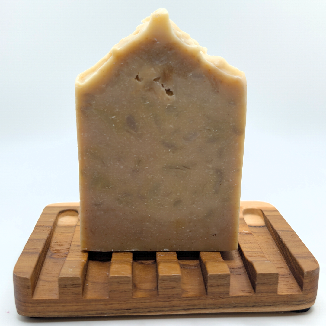 Bar of soap on a wooden soap dish against a white background
