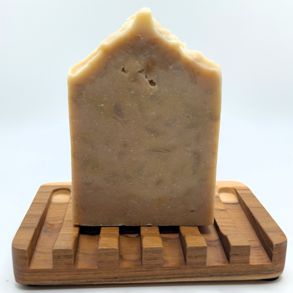 Bar of soap on a wooden soap dish against a white background