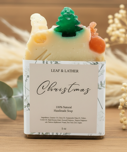 Handmade soap with Christmas design and 'Leaf & Lather' branding on a wooden background.
