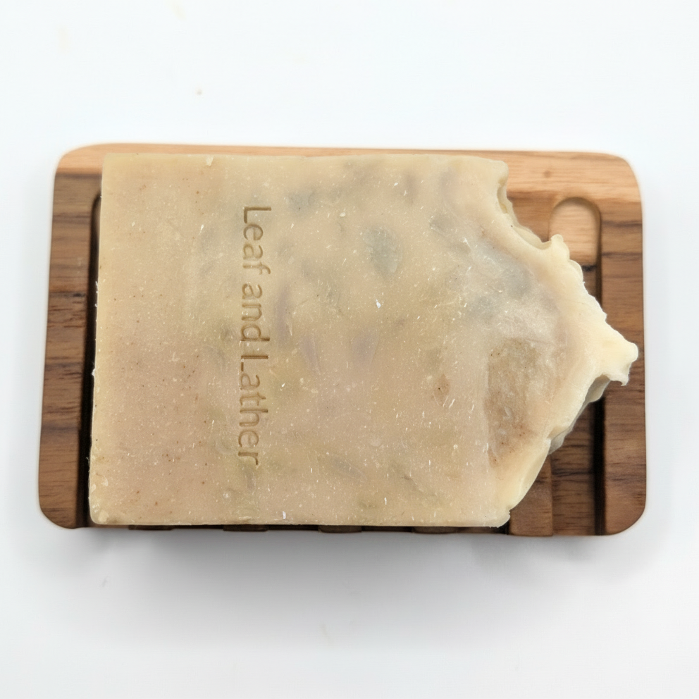 Bar of soap on a wooden soap dish with 'Leaf and Lather' branding on a white background