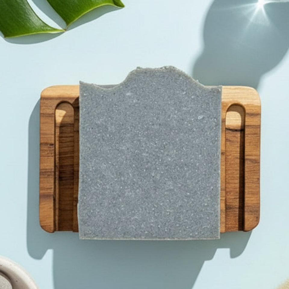 Gray stone on a wooden block with green leaves and a glass of water in the background