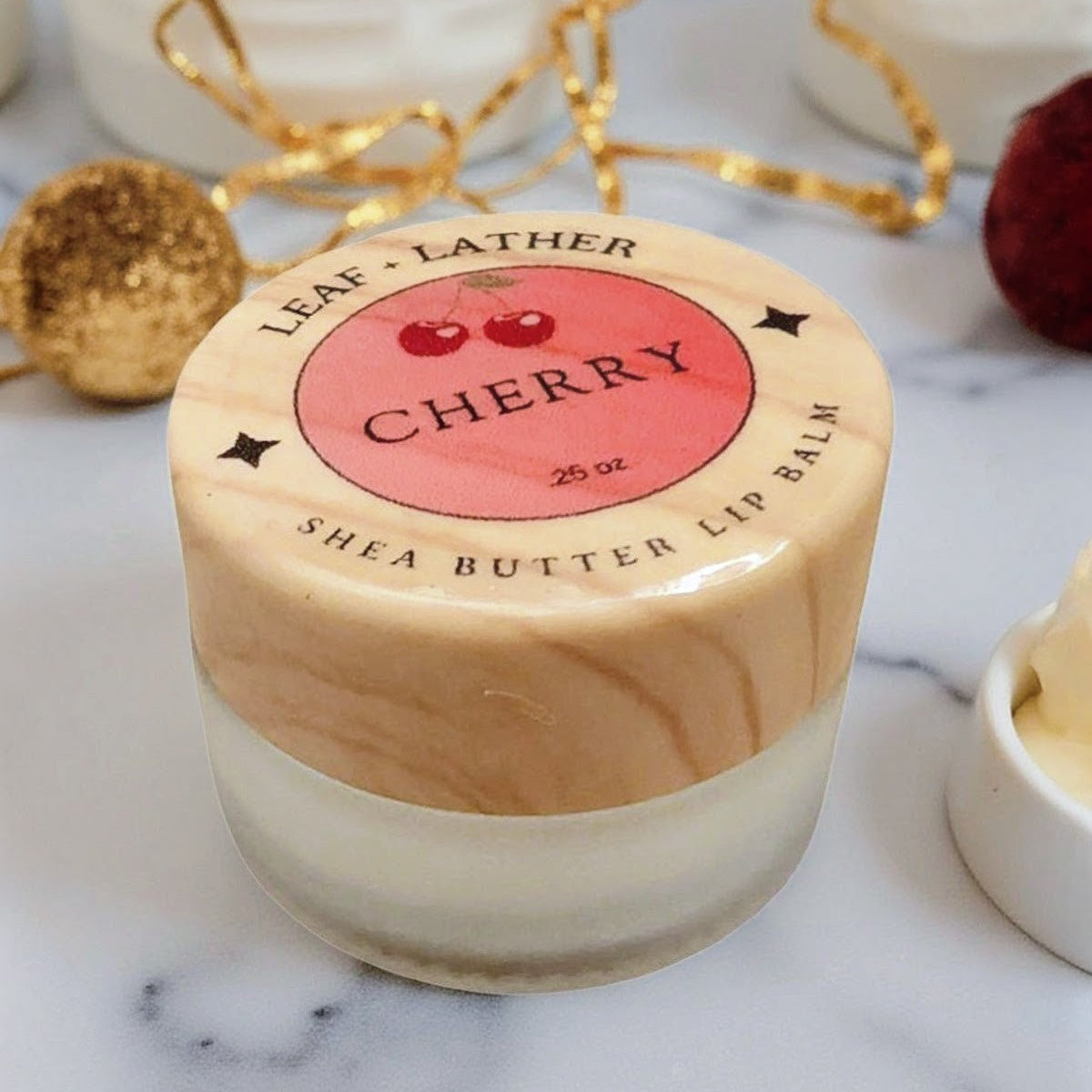 Shea butter lip balm with cherry flavor on a marble surface