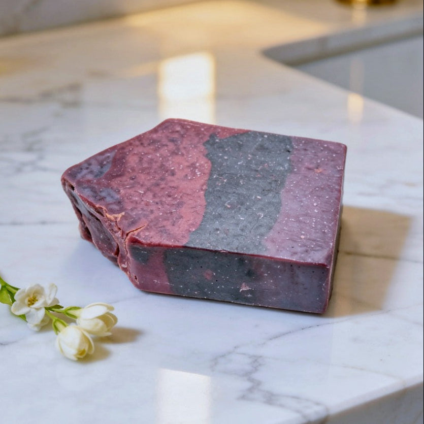 Purple soap bar on a marble countertop with white flowers