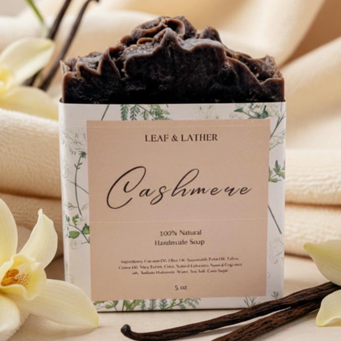 Handmade soap bar with 'Leaf & Lather' branding on a beige background with vanilla beans and flowers.