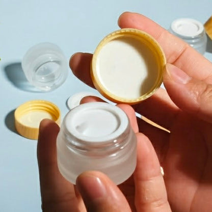 Person holding a small clear container with a yellow lid against a light blue background