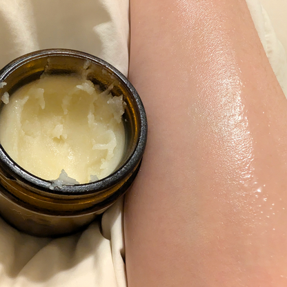 Jar of cream next to a person's arm with a smooth, moisturized appearance